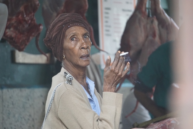 Older woman with a cigarette looking at the camera.